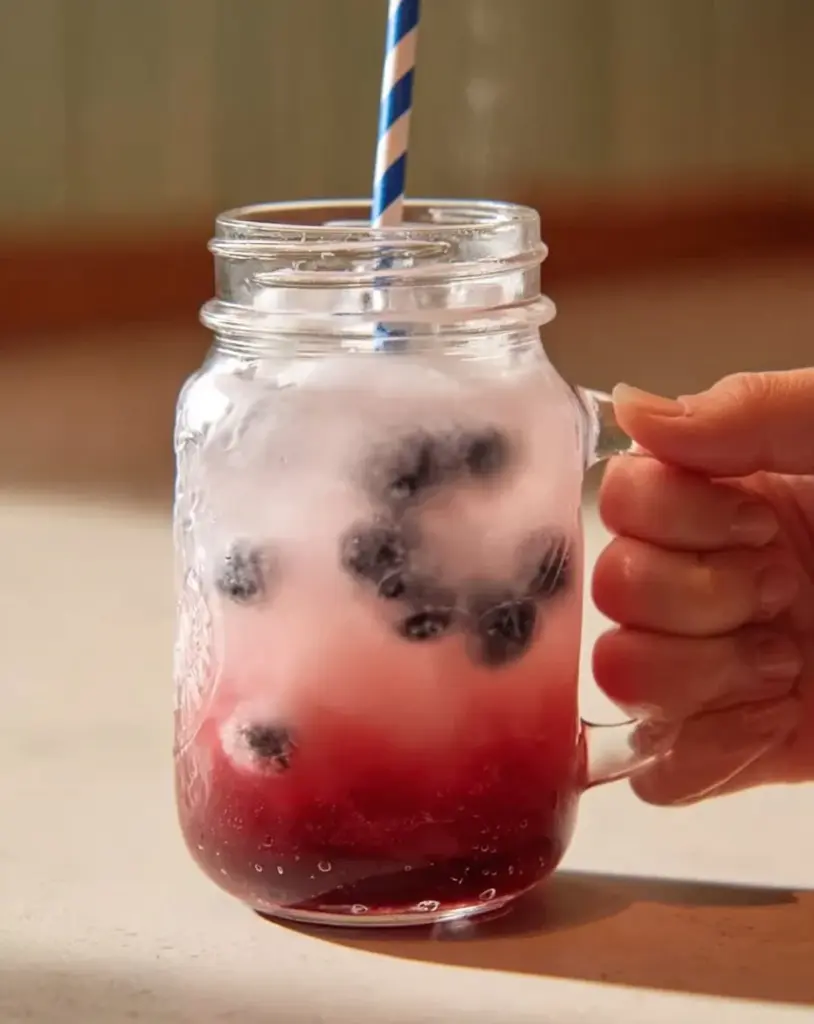 Sommerdrink aus eisgekühlten Himbeeren und Hibiskustee in einem Glas.